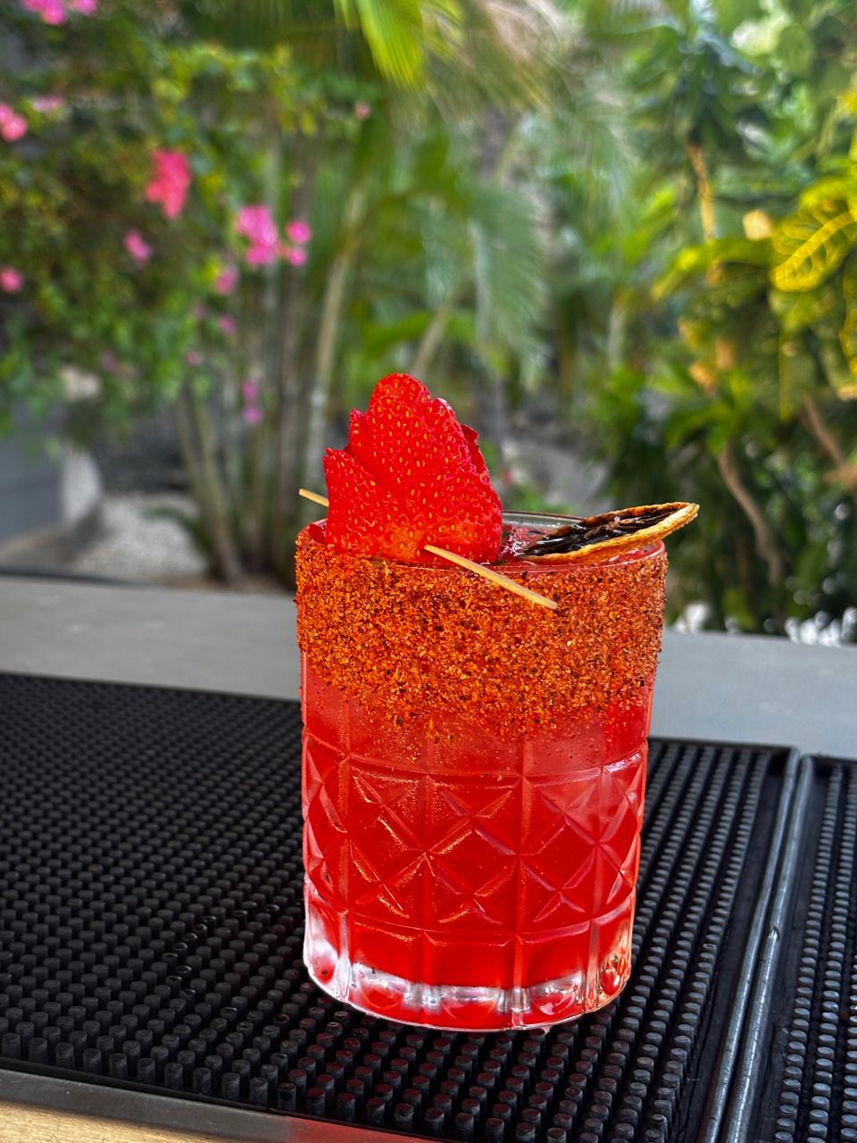 Coctel rojo de fresa con borde de chile y fresa deshidratada